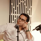 Young man recording a podcast in a professional studio setting with a microphone.